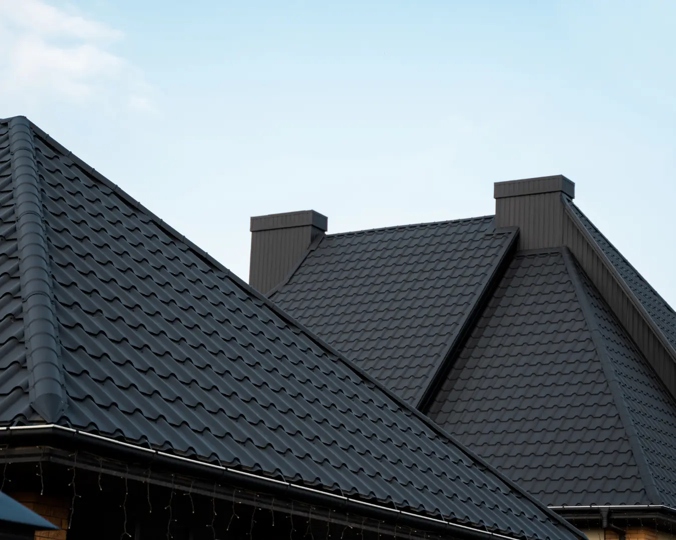 Dark architectural shingle roofline standing against an open sky