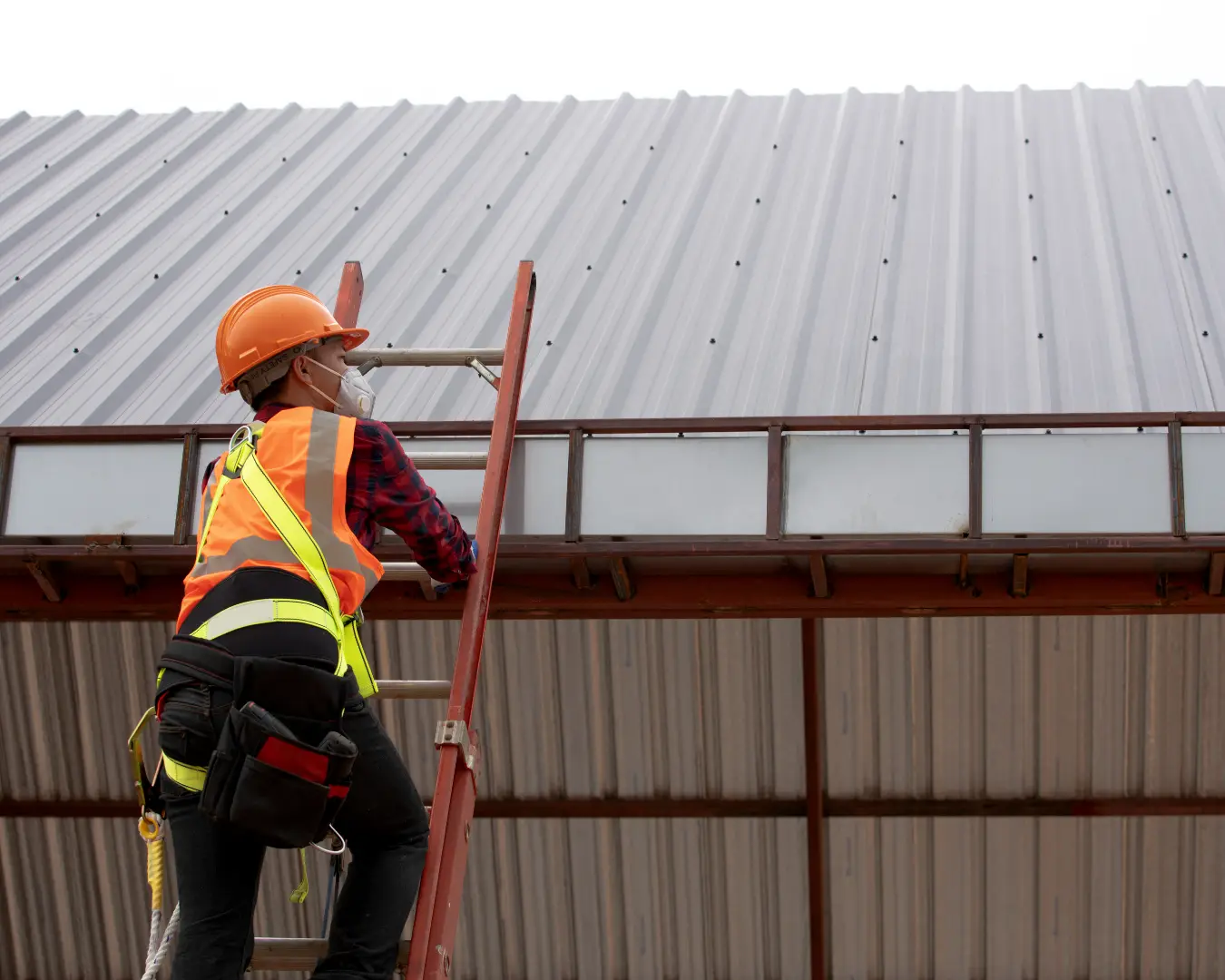 Roofing technician on a ladder performing a maintenance inspection