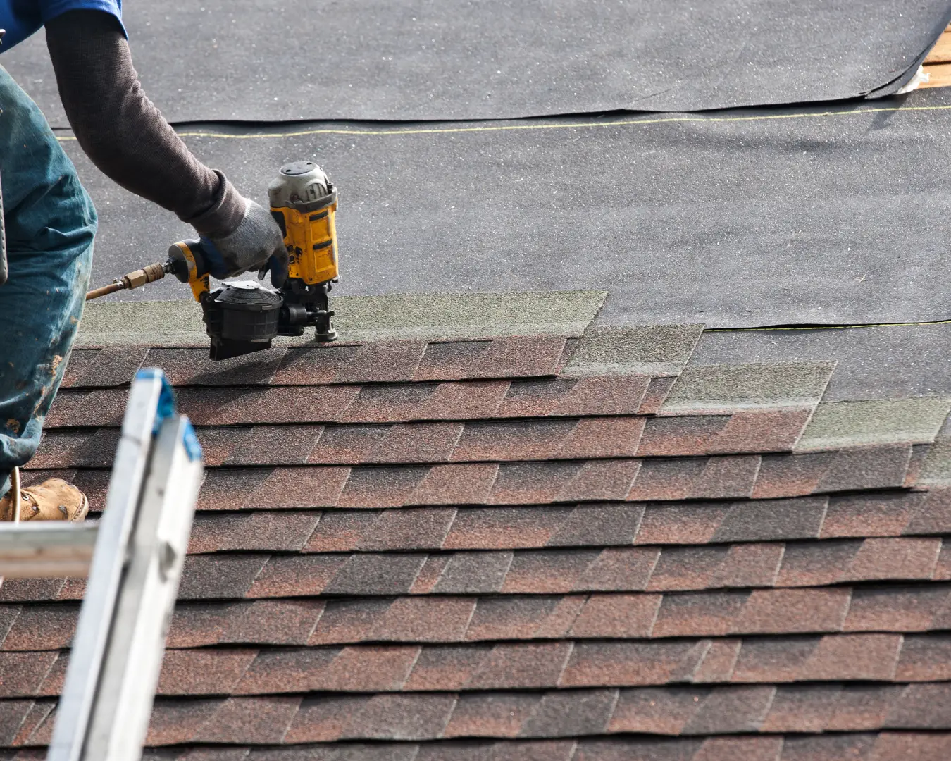 Roofer repairing asphalt shingles with a nail gun